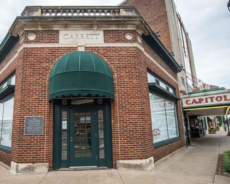 Genealogy Center entrance: a green wood door with glass panes an covered arch set into corner of a brick building with "GARRETT" inscribed above